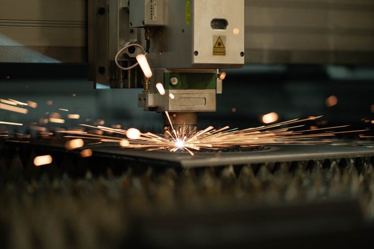 Fiber laser cutting head cutting sheet metal in a shower of sparks