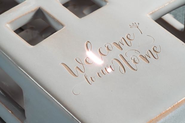 Boss UV laser engraving script lettering into a glazed ceramic house